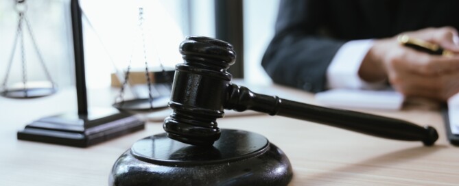Close-up of a judge’s gavel and scales of justice on a lawyer’s desk during a legal consultation.