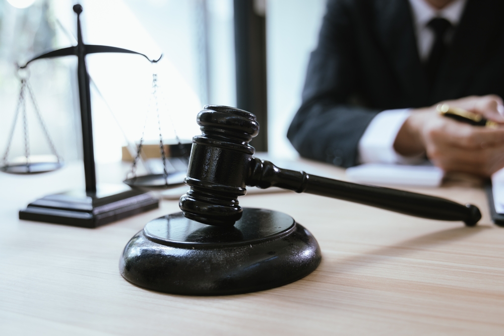 Close-up of a judge’s gavel and scales of justice on a lawyer’s desk during a legal consultation.