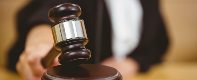 Hand about to bang gavel on sounding block in the court room