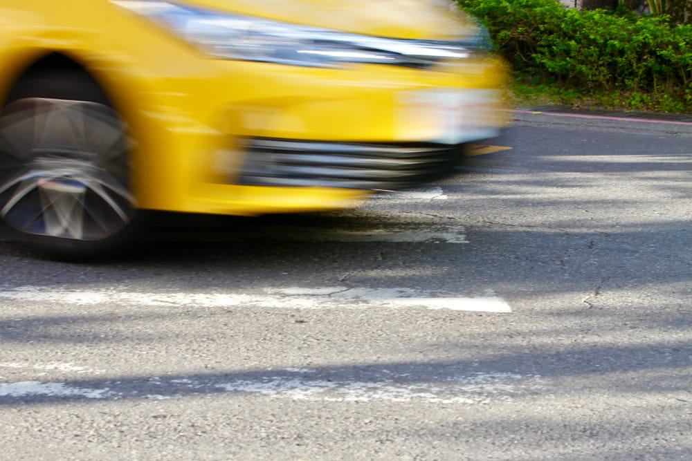 Yellow vehicle speeding through a crosswalk in Los Angeles, illustrating a pedestrian accident risk.
