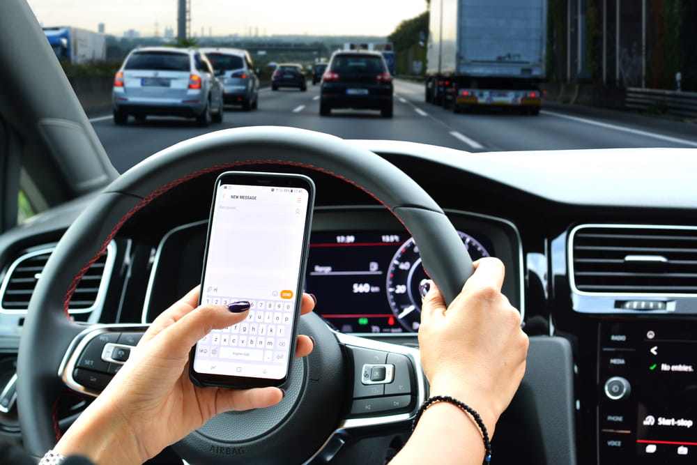 Driver sending a text message while driving on a busy highway in Los Angeles.